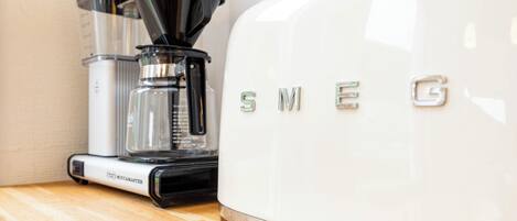 Una cafetera y un electrodoméstico blanco con el nombre de marca 'SMEG'.