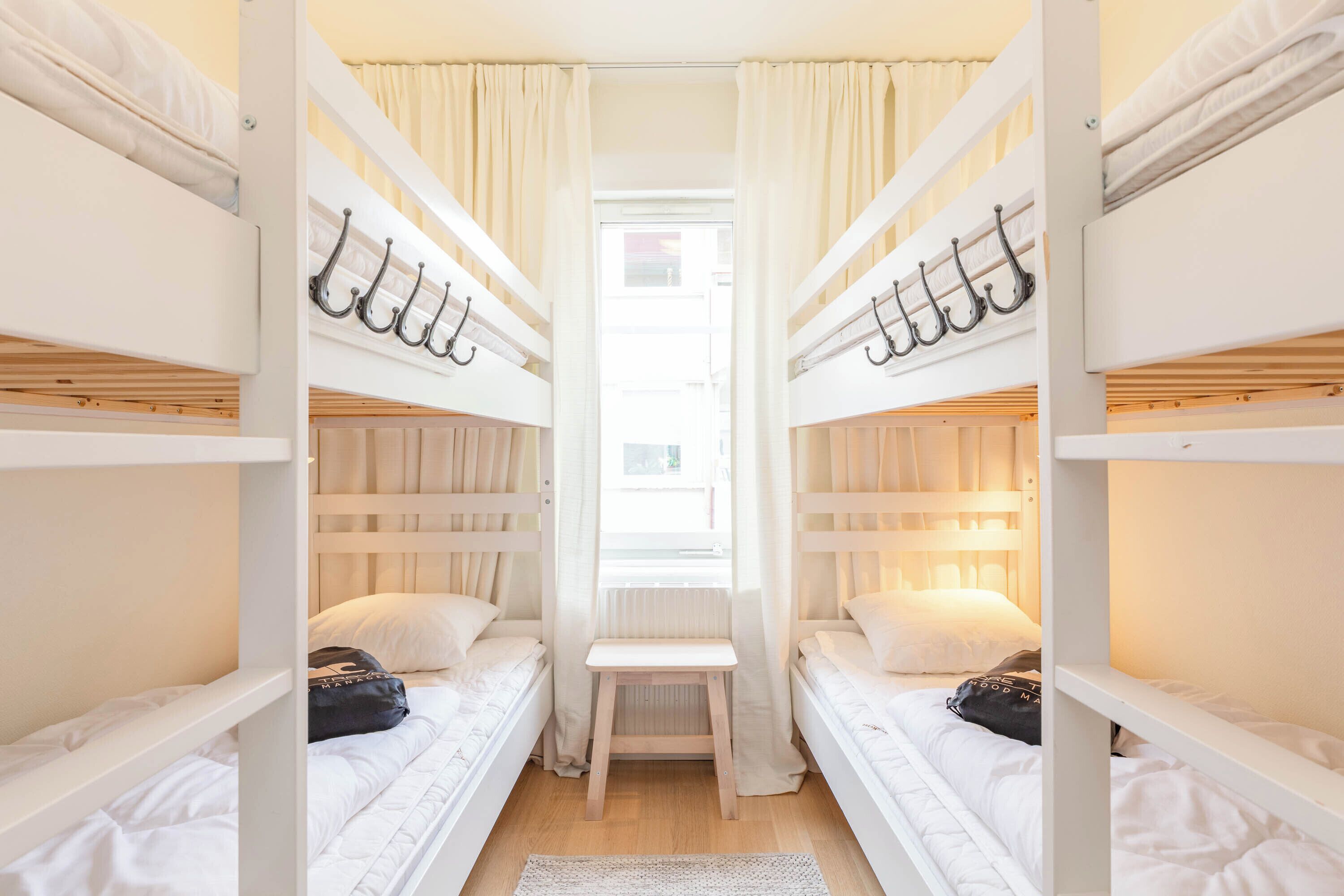A room with bunk beds, a small table, and a window with curtains.