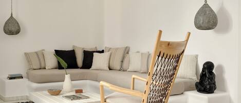 A living room with a wooden rocking chair, a white sofa, and a black statue.