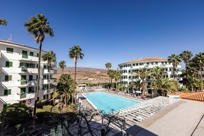 A hotel with a swimming pool, palm trees, and a mountainous backdrop. - Servatur Playa Bonita (San Bartolomé de Tirajana)
