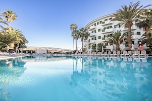Una piscina al aire libre, sombrillas, sillones reclinables de piscina