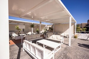 An outdoor seating area with white furniture and a covered patio.