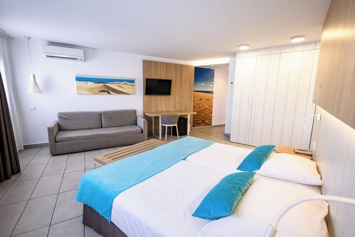Ein Hotelzimmer mit einem Bett, einer Couch, einem Schreibtisch und einem Fernseher.