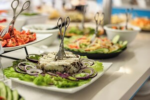 A buffet table with various dishes, including a slice of cake with a fork on top, surrounded by salad and other food items.