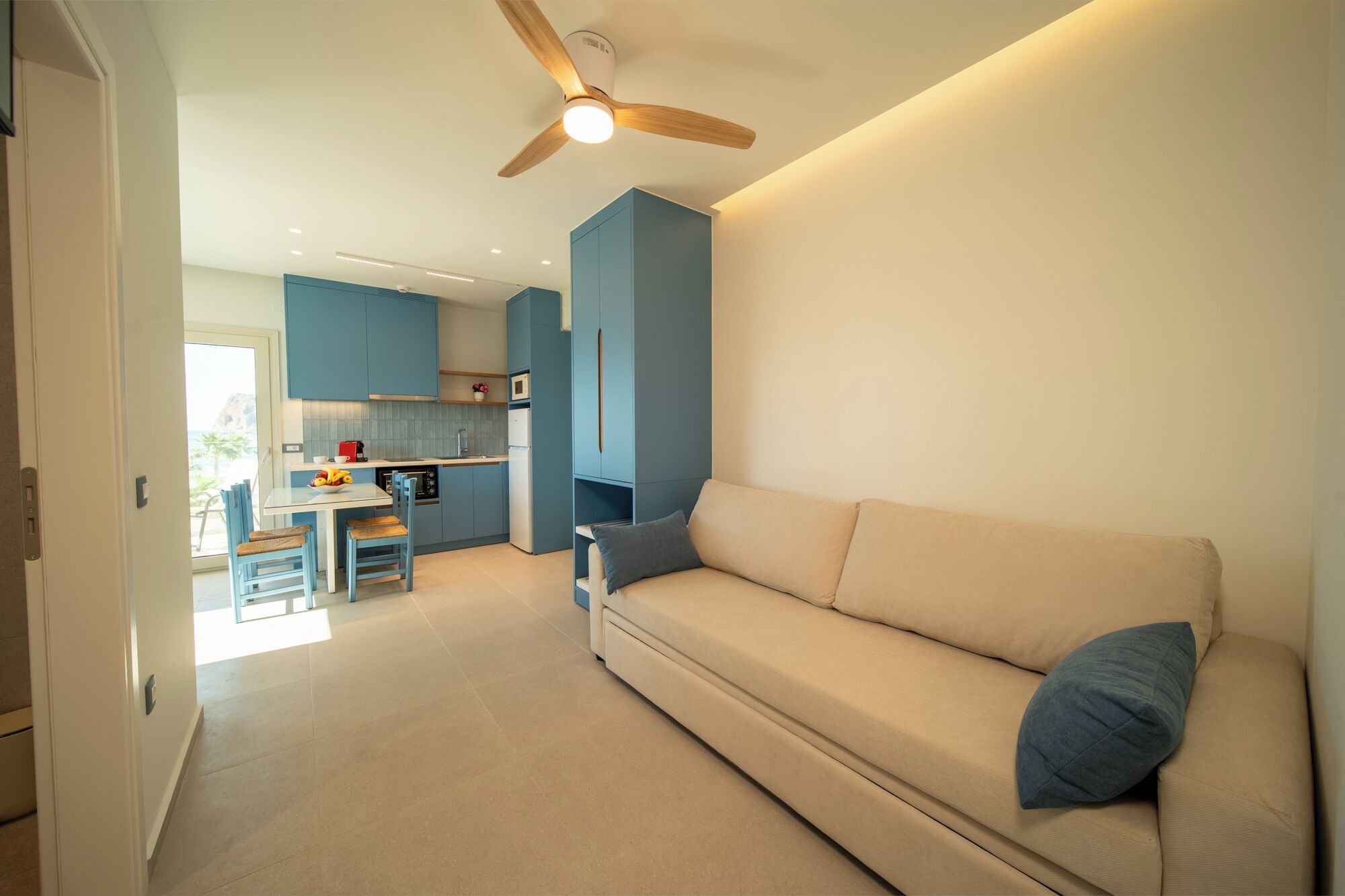 Una sala de estar moderna con un sofá color beige y un ventilador de techo.