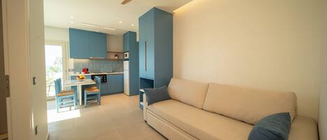 Una sala de estar moderna con un sofá color beige y un ventilador de techo.