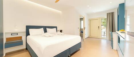 Quarto de hotel moderno com uma cama grande, ventoinha no teto e cozinha compacta.