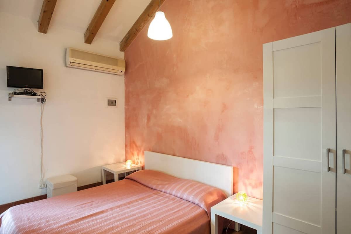 A bedroom with a bed, bedside tables, a TV, and a wardrobe.