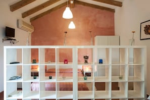 A room with a white shelving unit, a bed with pink bedding, and a wooden ceiling. - Come In Sicily - Pietramonaca (Acireale)