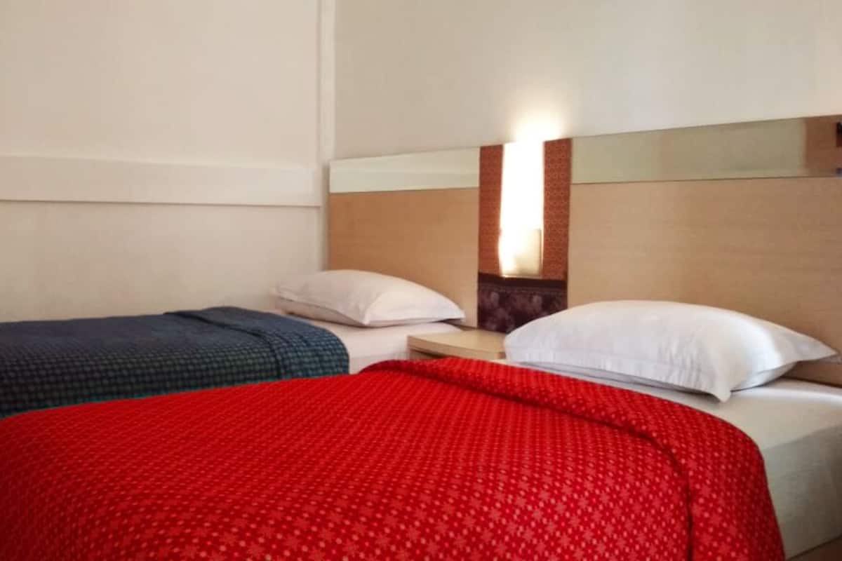 Une chambre d’hôtel avec deux lits, chacun recouvert d’une couvre-lit à motifs différents.