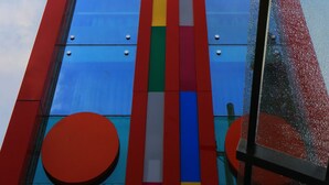 Un immeuble imposant, doté d’une façade colorée ornée de bandes verticales et de fenêtres rondes.