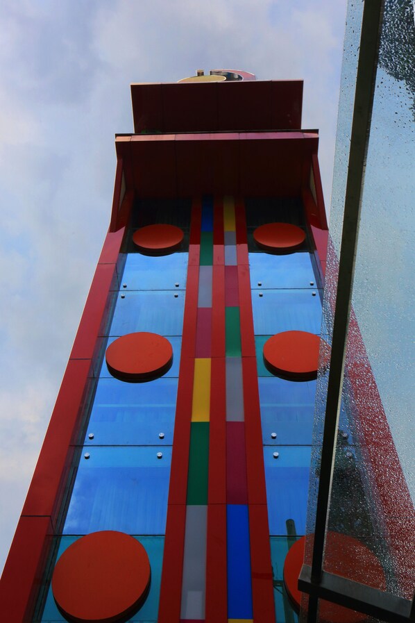 Un immeuble imposant, doté d’une façade colorée ornée de bandes verticales et de fenêtres rondes.