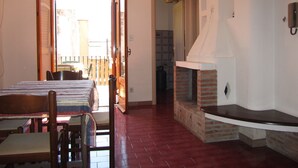A room with a dining table, chairs, a fireplace, and an open door leading to an outdoor area. - Come In Sicily - Al Mercato (Taormina)