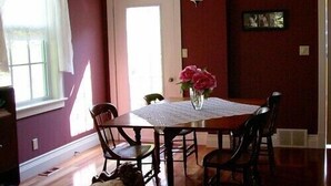 A dining area with a table and chairs, a chandelier, and a vase with flowers. - Antique Slumber Old Town Bed & Breakfast (Niagara-on-the-Lake)