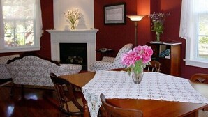 A dining room with a fireplace, a chandelier, and a table with a lace tablecloth. - Antique Slumber Old Town Bed & Breakfast (Niagara-on-the-Lake)