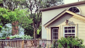 A house with a wooden deck, a small garden with red mulch, and a variety of plants. - Antique Slumber Old Town Bed & Breakfast (Niagara-on-the-Lake)