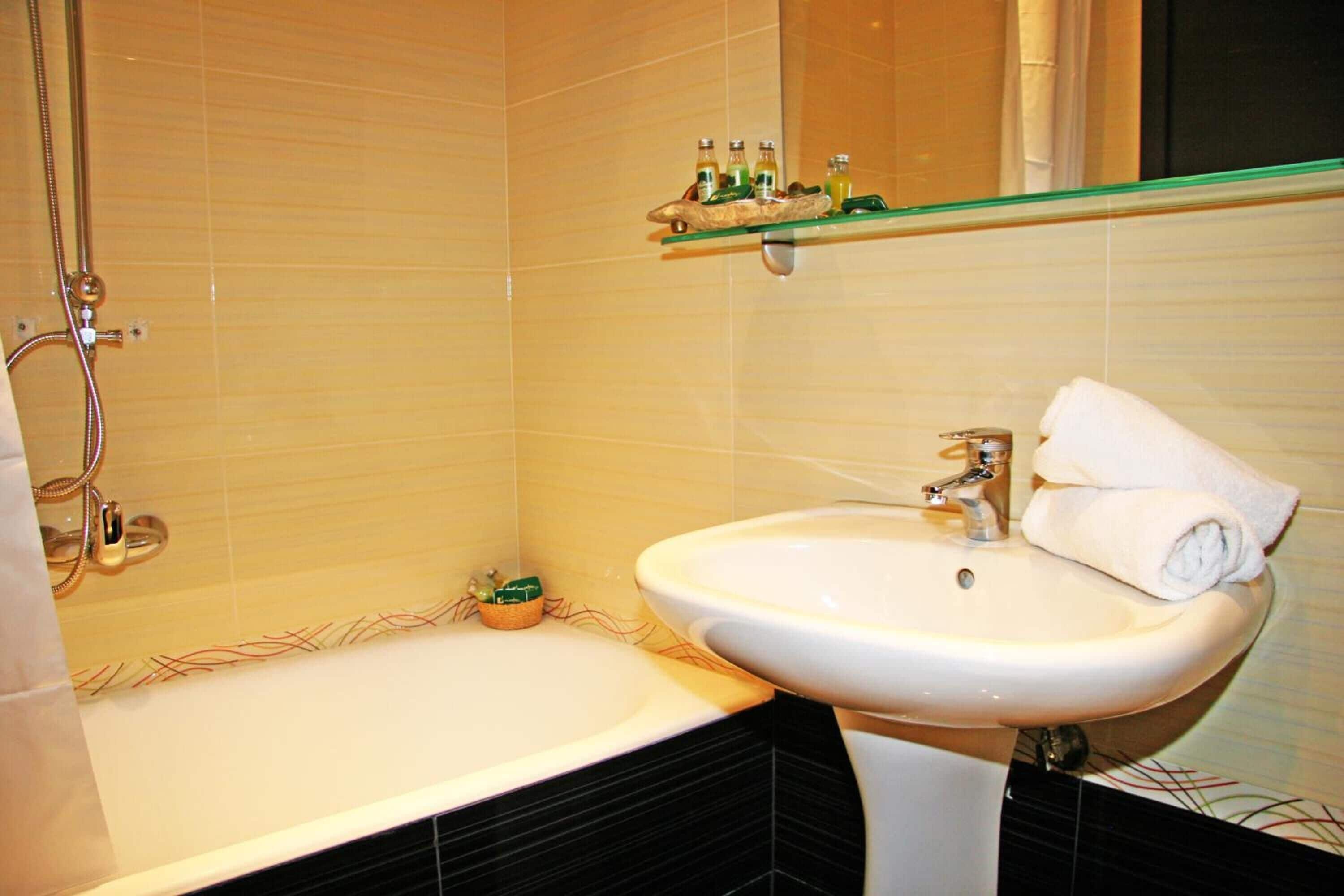 Un baño con bañera, lavamanos y estante con artículos de aseo.