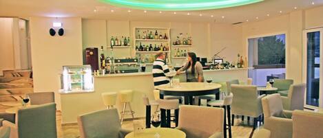 A bar area with seating, a bartender, and shelves of bottles.