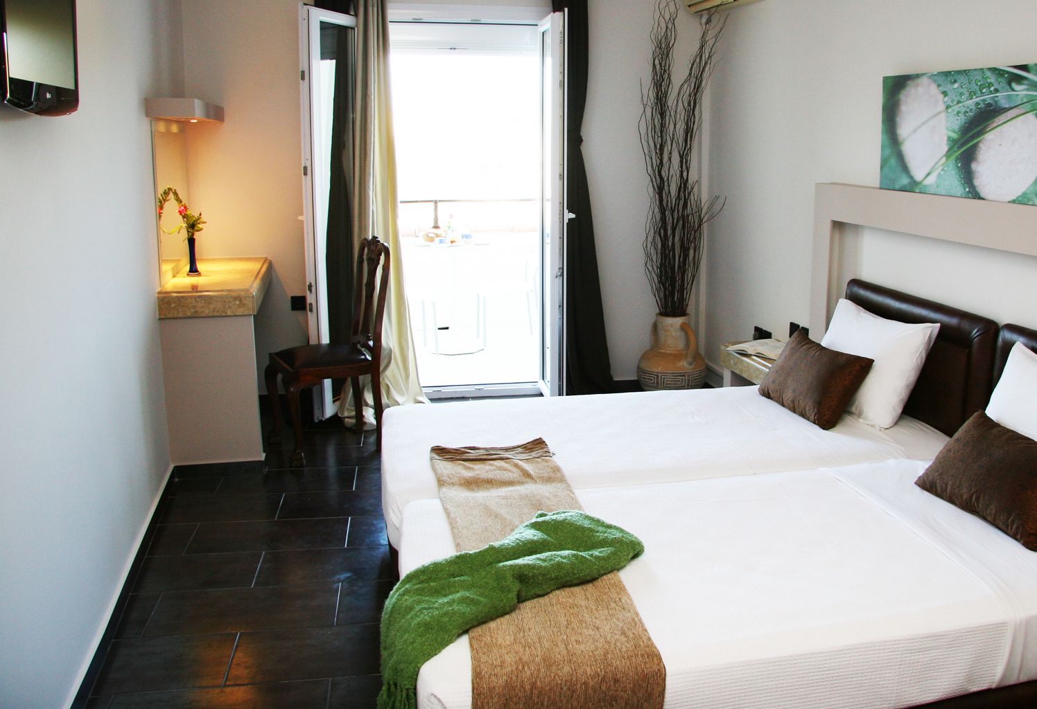 Habitación de hotel con una cama grande, una silla, un escritorio con lámpara y vistas al exterior.