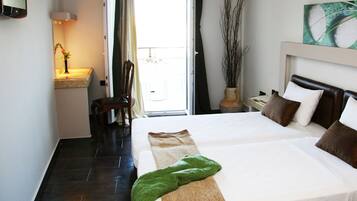 Habitación de hotel con una cama grande, una silla, un escritorio con lámpara y vistas al exterior.