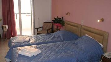 Habitación de hotel con dos camas, una silla, una planta y un teléfono en la mesita de noche.