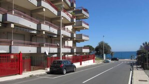 A multi-story residential building with balconies, a red gate, and a clear view of the sea. - Come In Sicily - Beachfront Sant'Alessio (Sant'Alessio Siculo)
