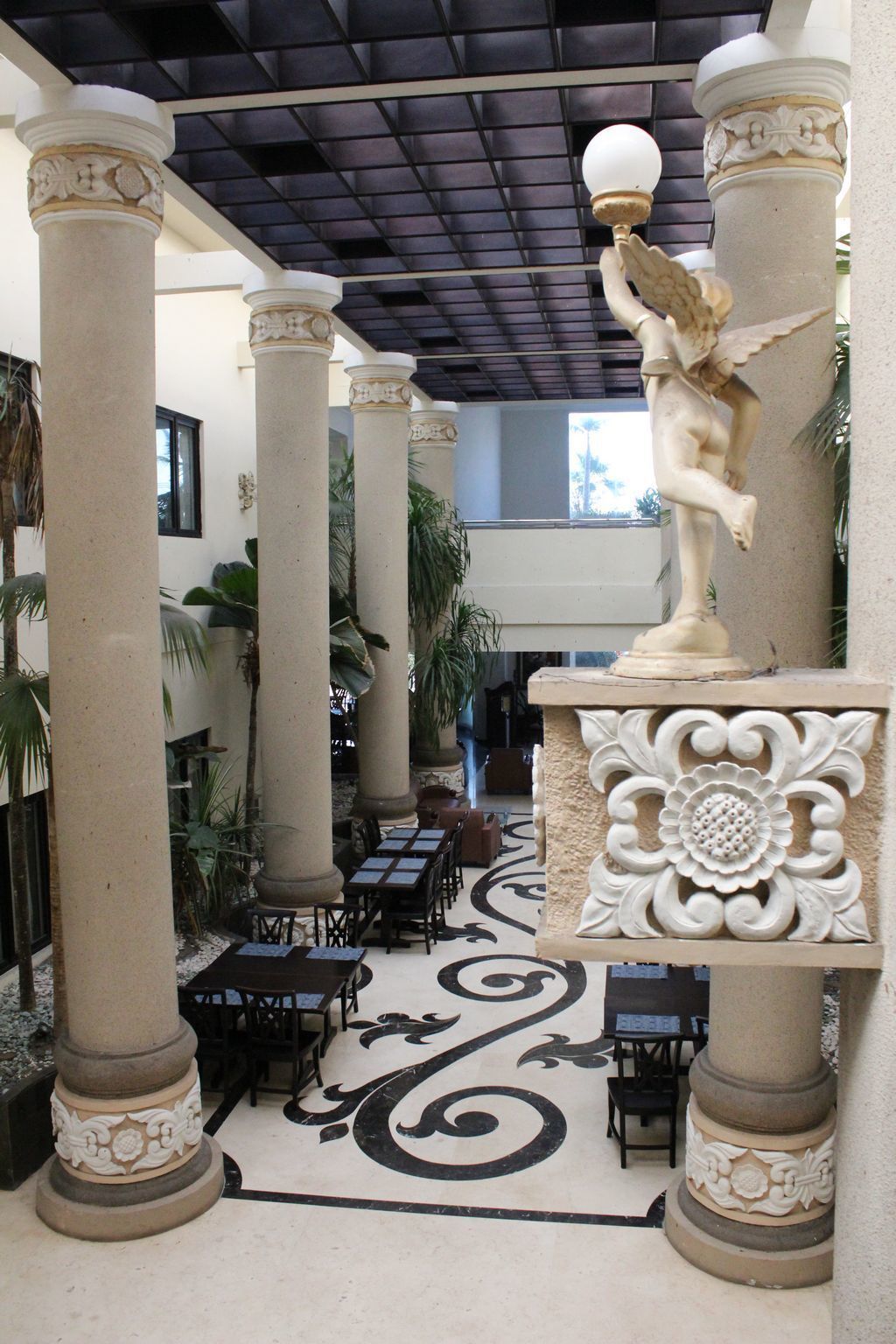 Un vaste espace intérieur doté de hauts piliers, d’une statue centrale et d’un sol orné de motifs.
