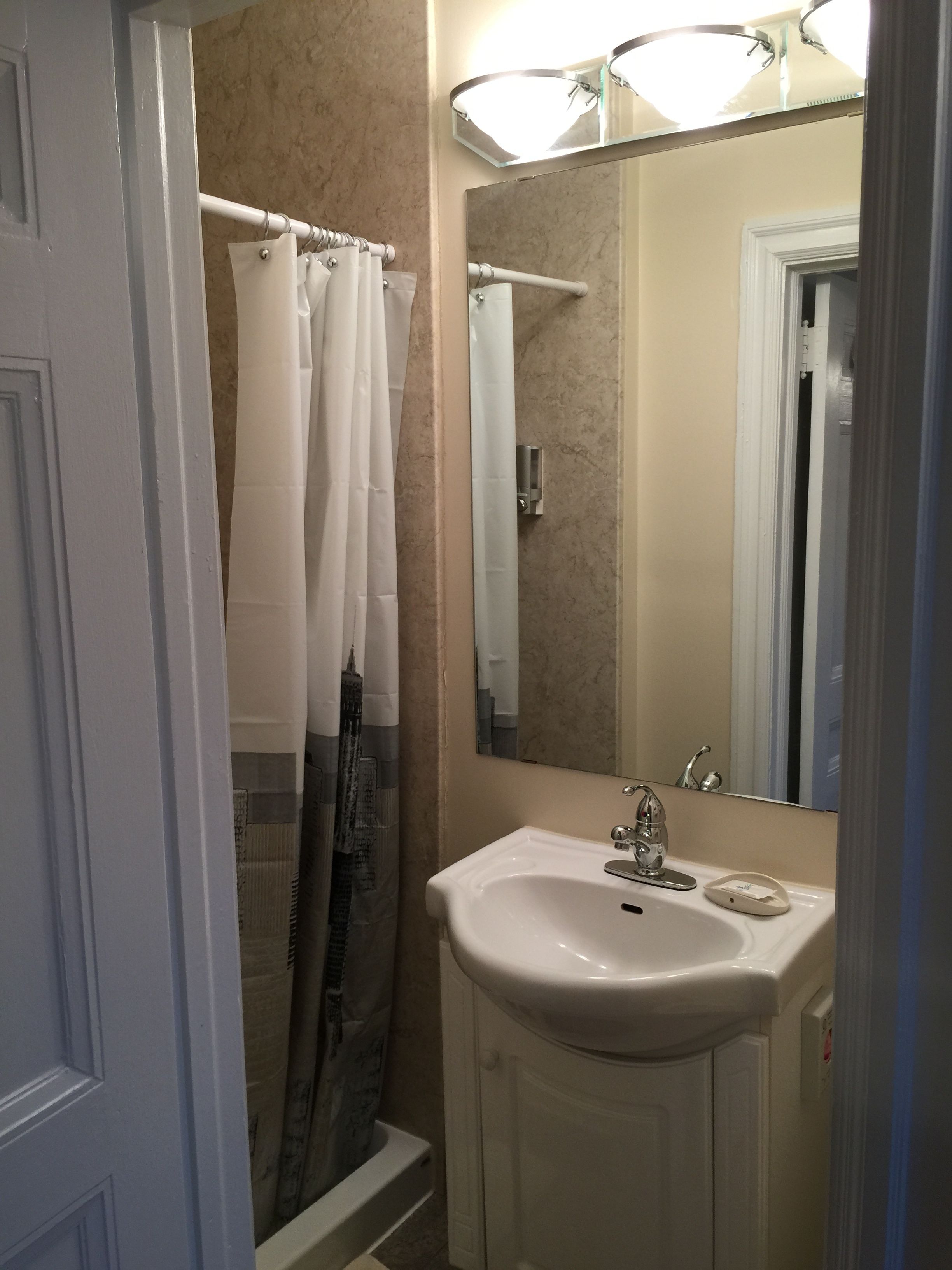 A bathroom with a shower, a sink, and a mirror.