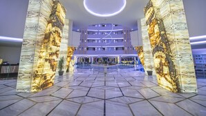 Un hall d’hôtel doté d’un atrium central, de colonnes en marbre et d’un design moderne au niveau du plafond.