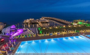 A large outdoor swimming pool with a view of a waterfront promenade and a historic building. - Mary Hotels Alanya - All inclusive (Alanya)