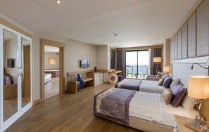 A hotel room with two beds, a desk, a TV, and a large window with a view. - Mary Hotels Alanya - All inclusive (Alanya)
