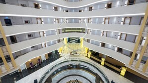 Un atrium d’hôtel à plusieurs niveaux, doté d’un escalier en colimaçon central, de nombreux balcons et d’un sol en marbre.