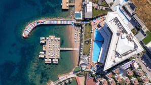 Vue aérienne d’une station balnéaire dotée d’un port de plaisance, d’une plage et de bâtiments modernes.