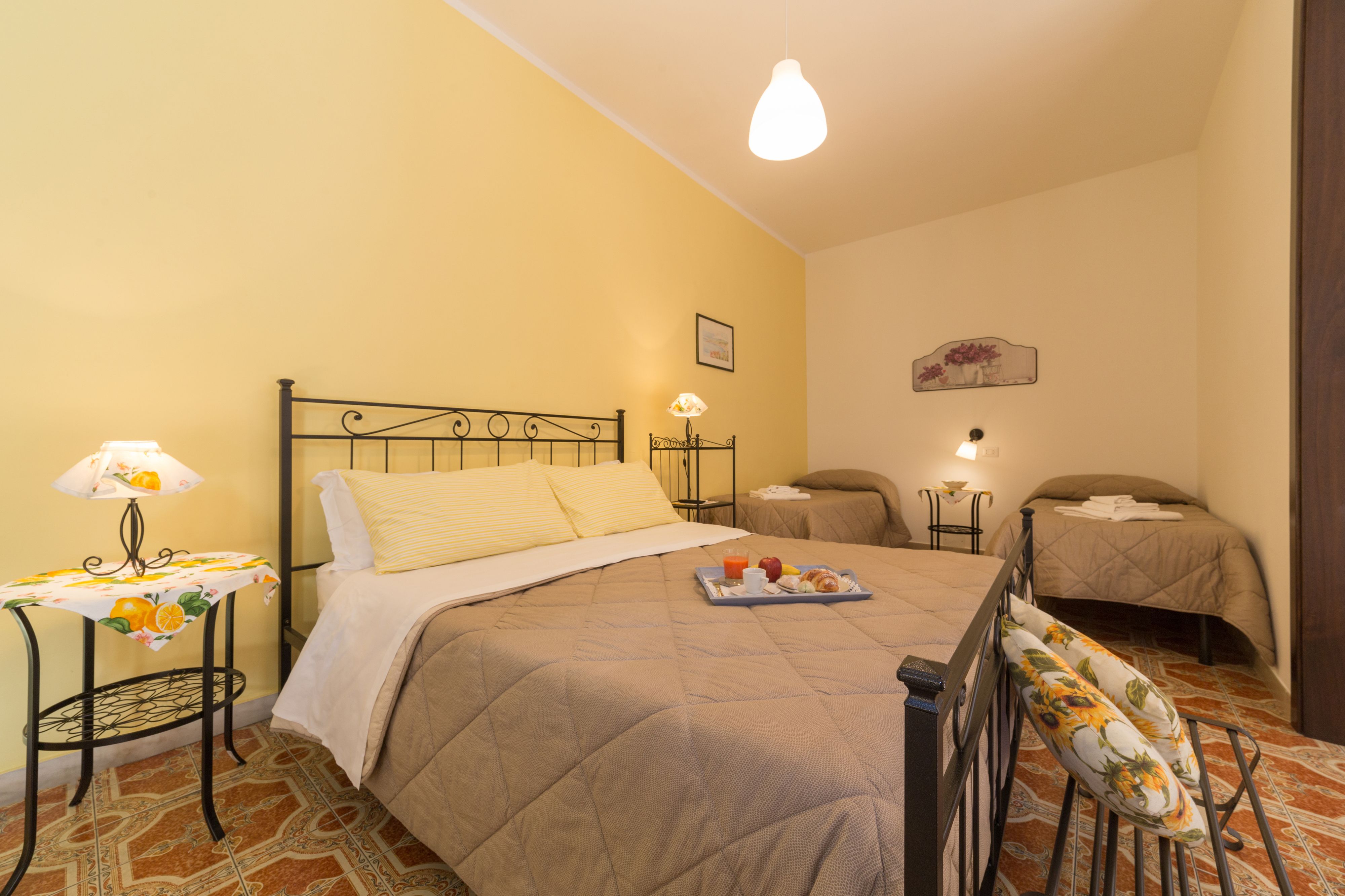 Un dormitorio con una cama, mesitas de noche, una lámpara y una bandeja con alimentos para el desayuno.