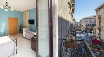 Una camera da letto con un letto, una televisione e un balcone con piante in vaso.