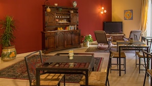 A living room with a wooden cabinet, a television, a dining table with chairs, and a potted plant. - Catania Inn (Catania)