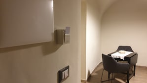 A room with a dining table and chairs, a wall-mounted light switch, and a small cabinet. - Catania Inn (Catania)