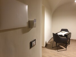 Una stanza con un tavolo da pranzo e sedie, un interruttore della luce fissato al muro e un piccolo armadietto.