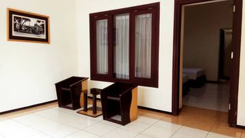 Um quarto com soalho em mosaico, uma mesa de madeira com cadeiras, uma janela com cortinas e um quadro na parede.