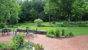 A patio with outdoor seating, surrounded by a well-maintained garden and a lawn. - King Hill Inn & Kitchen (New London)