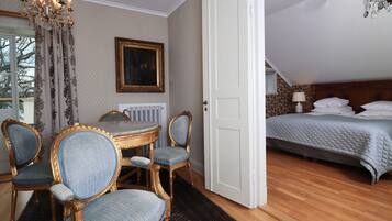 Una habitación con una mesa de comedor, sillas, una araña y una cama, con vistas al exterior.