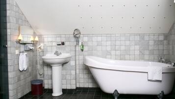 Un baño moderno con una bañera independiente, un lavabo sobre pedestal y un tocador con espejo e iluminación.
