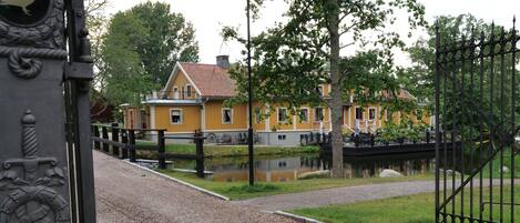 A yellow building with a red roof, a pond, and a bridge.