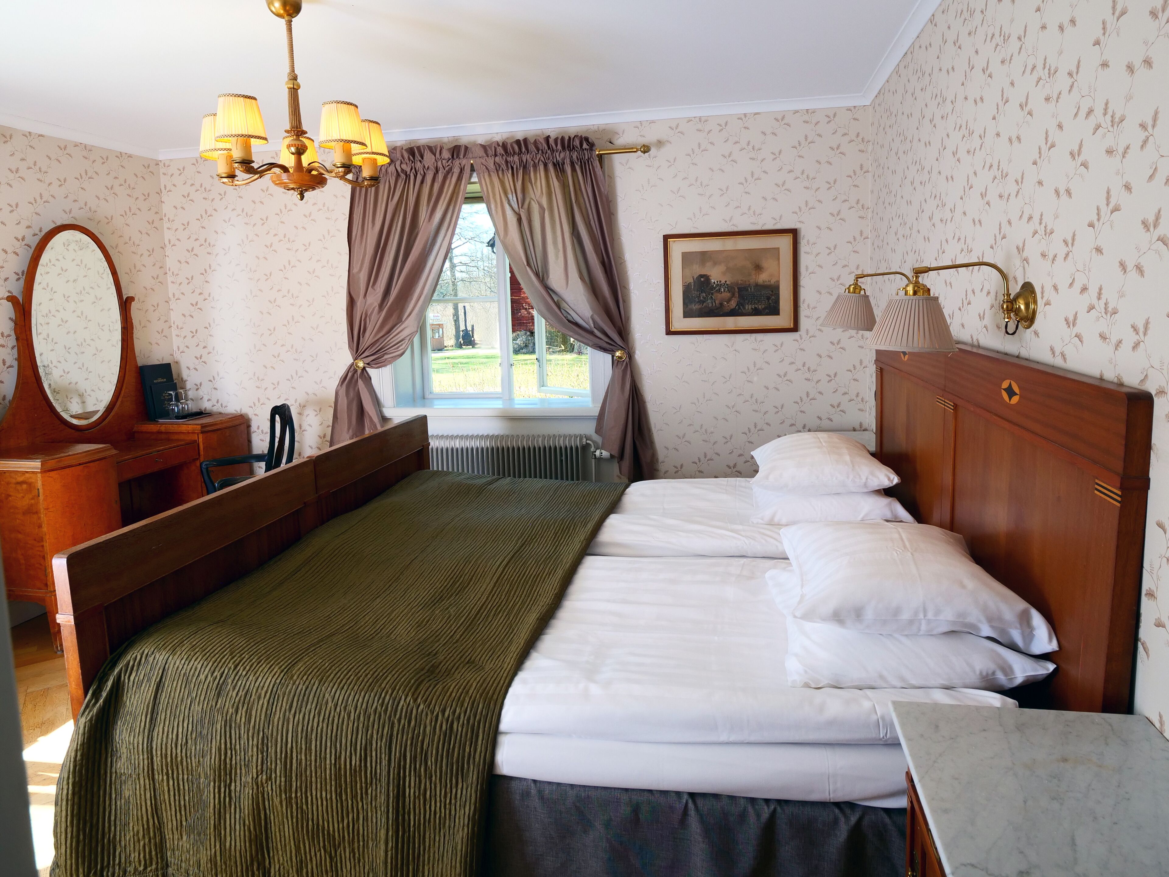 A hotel room with a large bed, a wooden dresser, a mirror, a window with curtains, and a painting on the wall.
