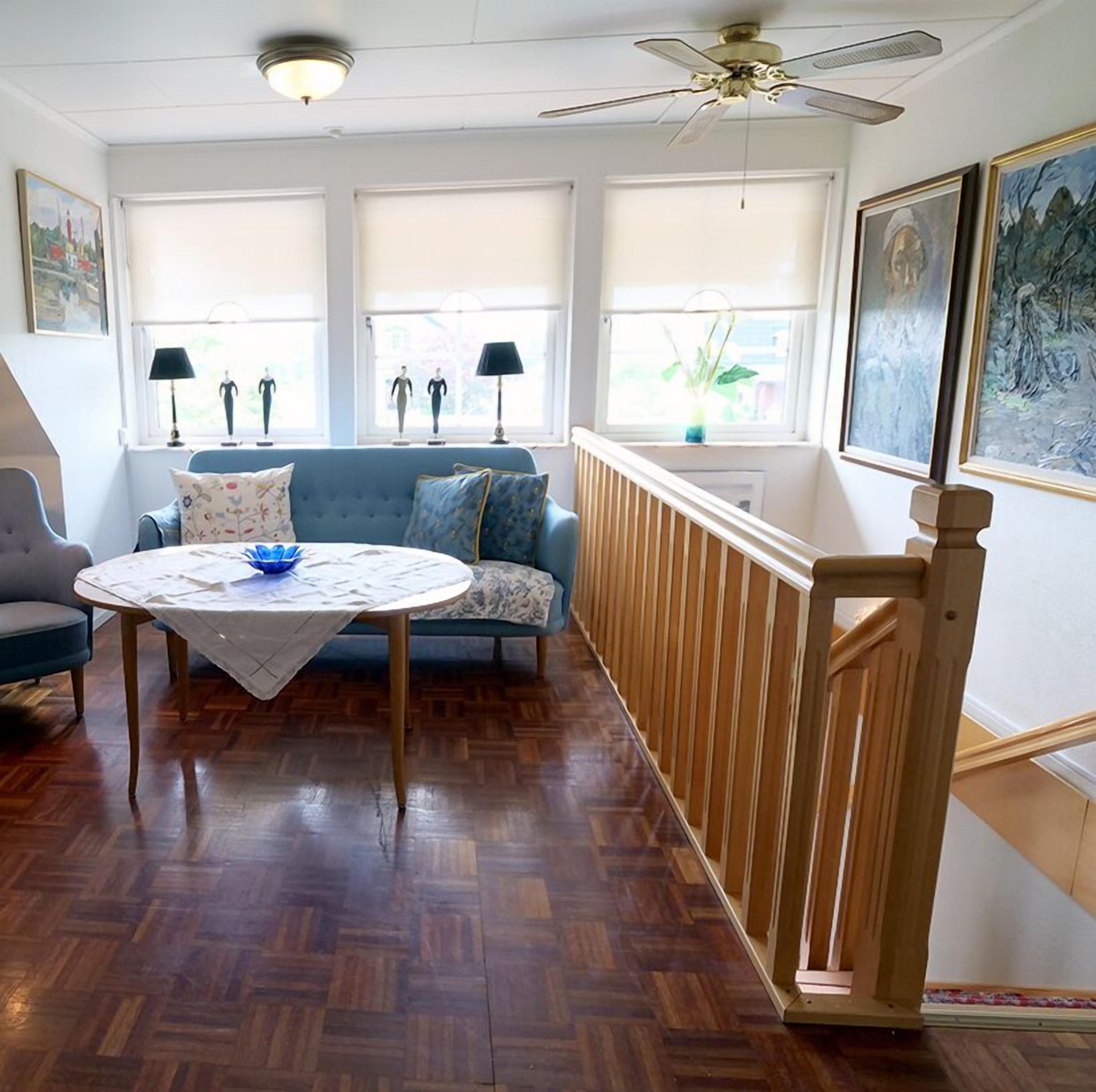 A room with a blue sofa, a round table with a white tablecloth, and a wooden railing.