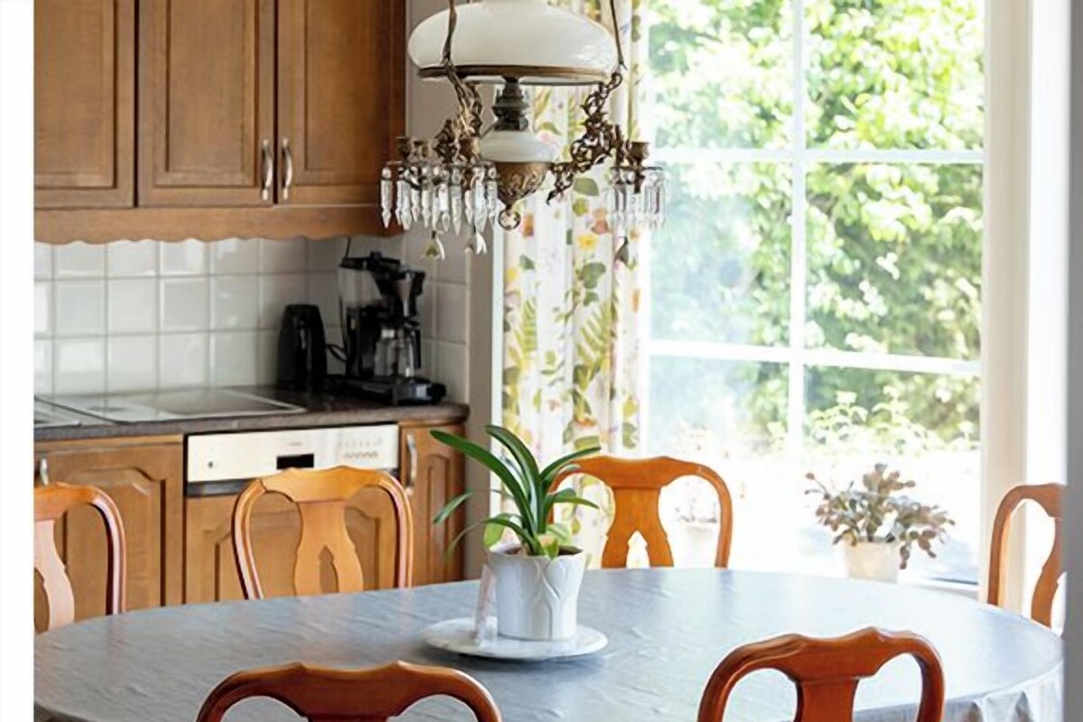 A dining area with a round table, wooden chairs, and a chandelier.