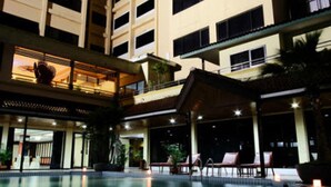 A hotel with a swimming pool, multiple floors, and outdoor seating areas. - Regent's Park Hotel (Malang)
