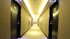 A hotel hallway with doors numbered 315 and 314, featuring a carpeted floor and overhead lighting. - Regent's Park Hotel (Malang)
