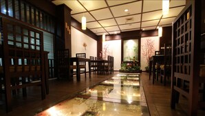 A traditional Japanese-style interior with tatami mat flooring, wooden furniture, and a central water feature. - Regent's Park Hotel (Malang)