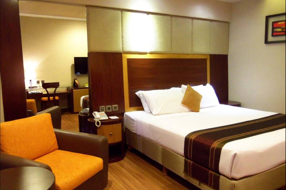 A hotel room with a bed, a desk, a chair, and a telephone.